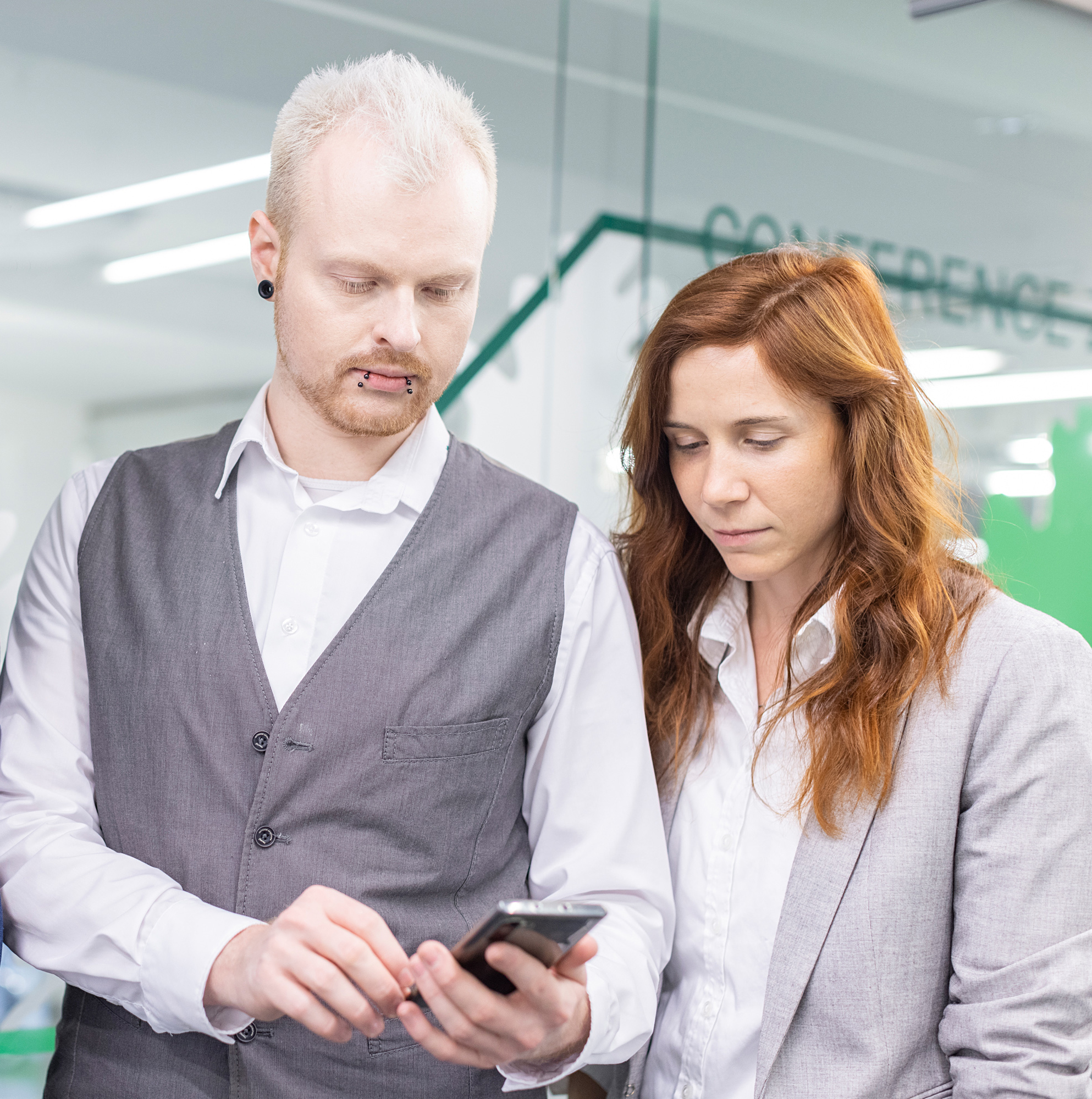 Mitarbeiter und Mitarbeiterin von Biohealths Regulatory Affairs Abteilung beraten sich bei einem Blick ins Smartphone