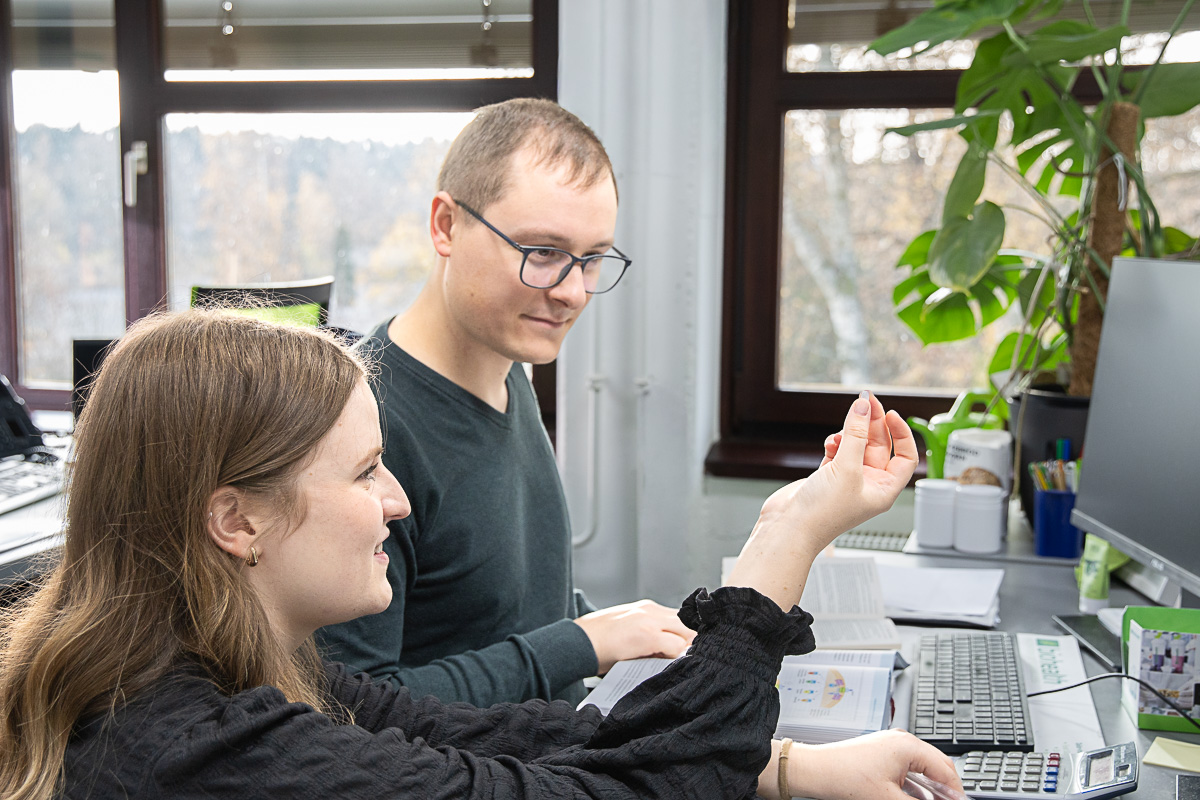Zwei Regulatory Affairs Manager sitzen gemeinsam vor dem PC und begutachten eine Kapsel
