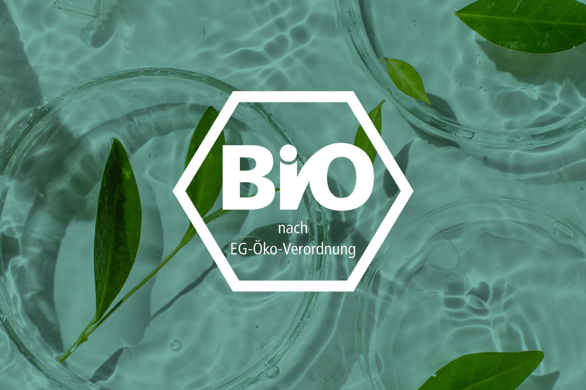 Blätter schwimmen in klarem Wasser. Darauf in weiß das Bio Logo