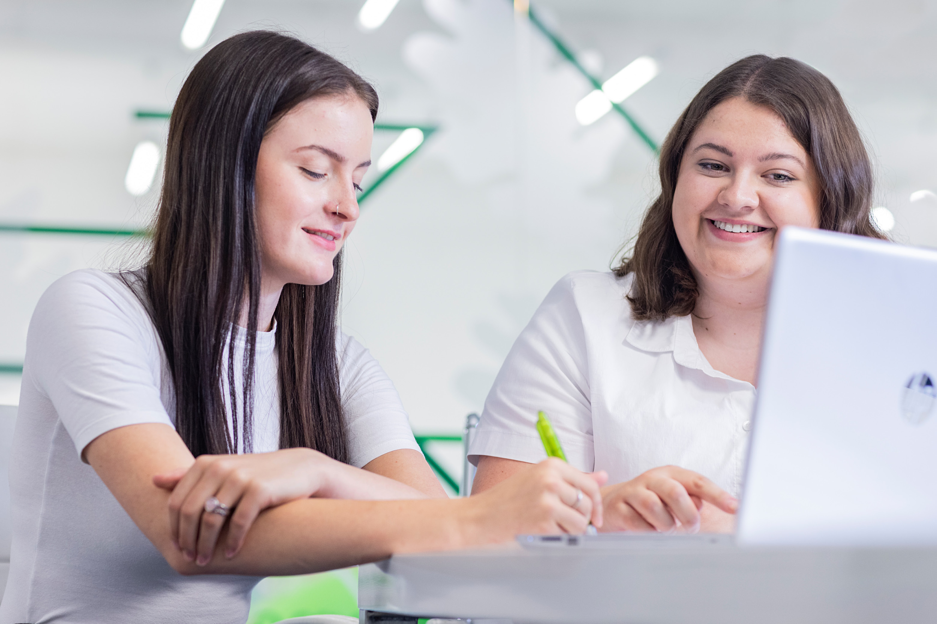 Auszubildende sitzt mit ihrer Ausbilderin zusammen im Gespräch, auf dem Tisch steht ein Laptop