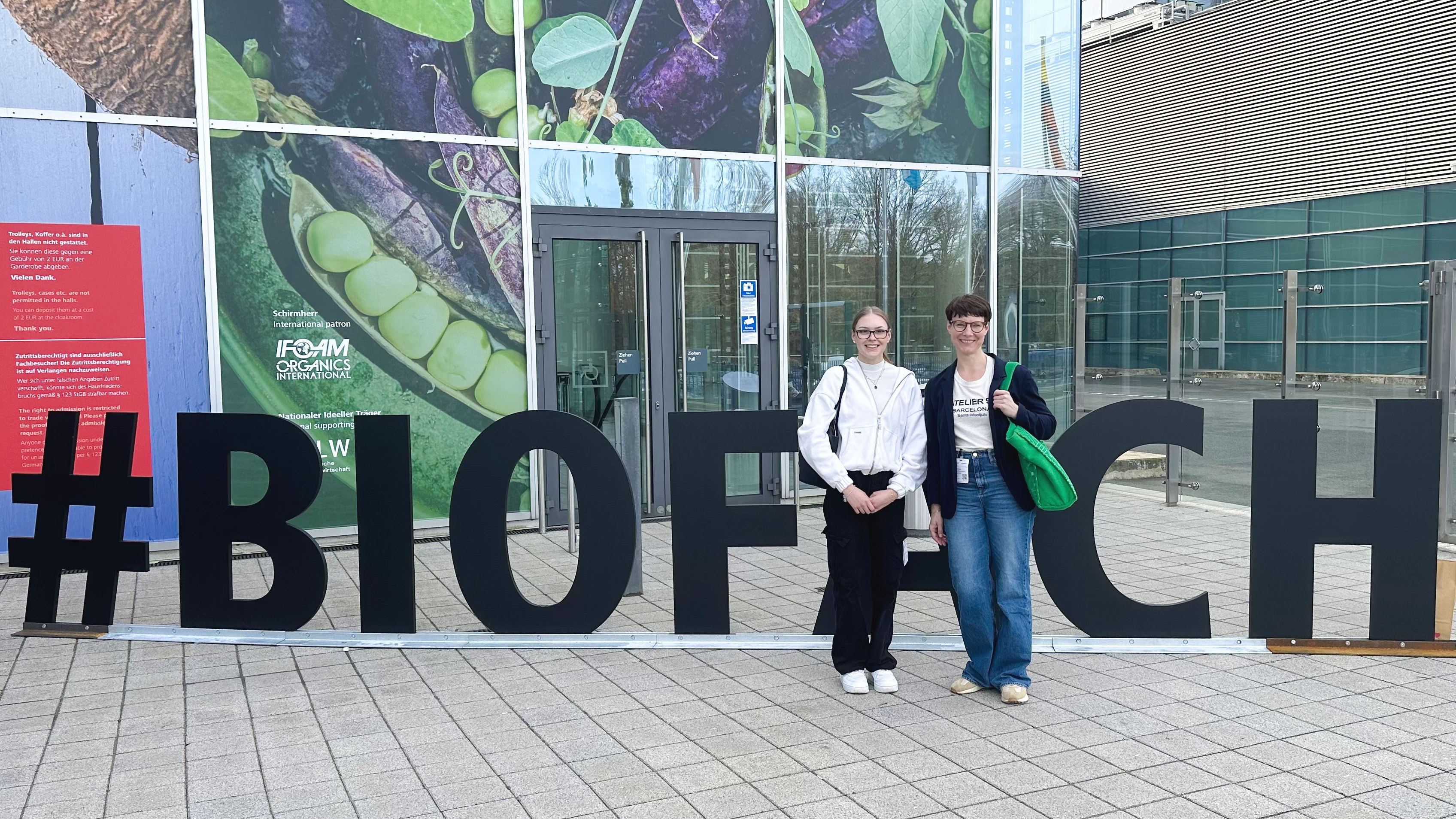 Foto von 2 Mitarbeiterinnen, die vor einem mannshohen Schriftzug #BIOFACH stehen