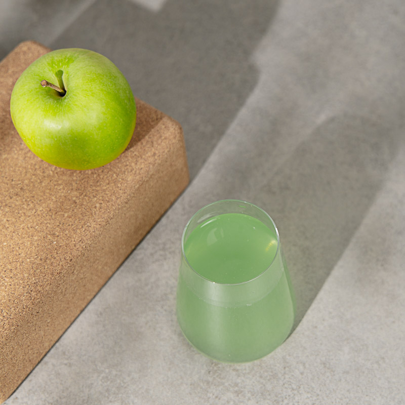 Grüner Private Label Energy Drink von oben, dazu ein grüner Apfel und viel Schattenspiel