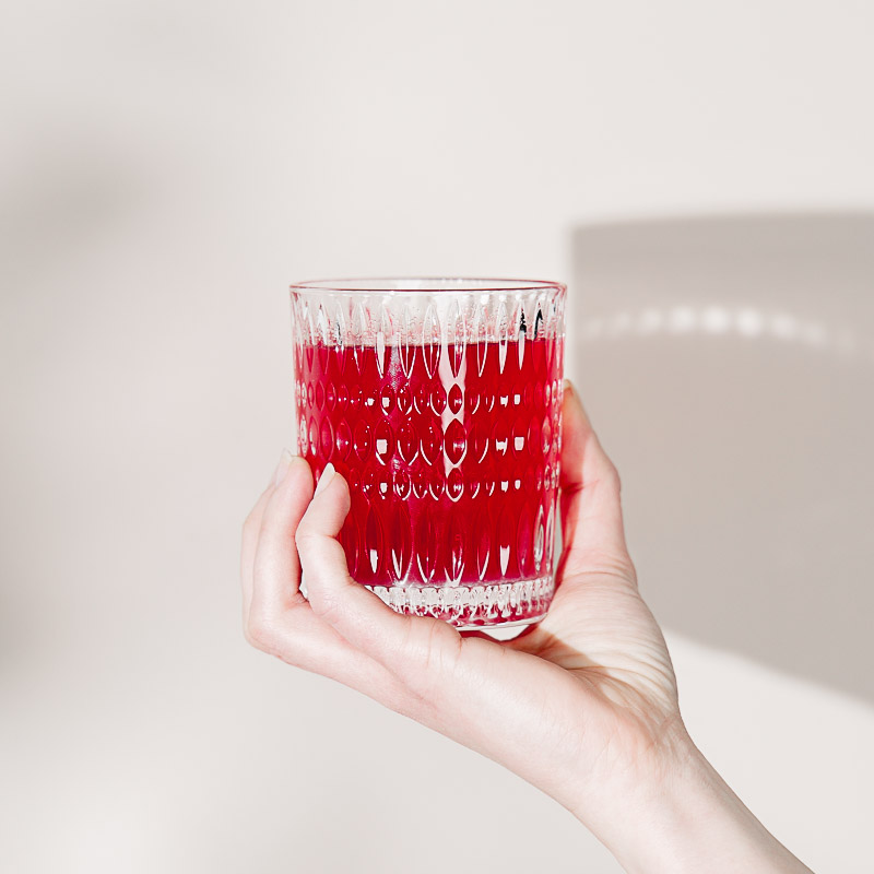 Eine Hand hält ein Glas mit "Happy Hydration" als Beispiel für elektrolythaltige Getränke