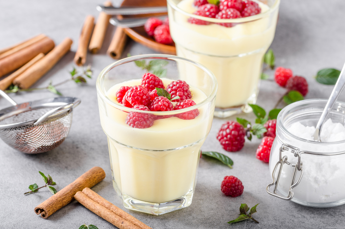 Pudding im Glas, darauf frische Früchte. Außenrum Kochutensilien