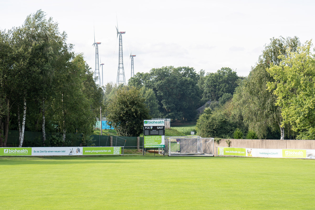 Bild des Fußballplatzes des FC Eintracht Münchberg ohne Spieler. Im Hintergrund die Bandenwerbung von Biohealth